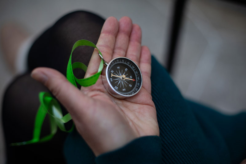 Compass in-hand with green ribbon